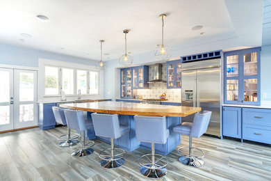Foto de cocina costera con armarios con paneles lisos, puertas de armario azules y encimera de madera