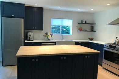 Example of a cottage kitchen design in Other with shaker cabinets, blue cabinets, wood countertops and white backsplash