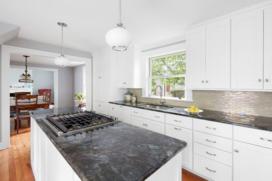 Enclosed kitchen - large transitional l-shaped medium tone wood floor and beige floor enclosed kitchen idea in Baltimore with an undermount sink, recessed-panel cabinets, white cabinets, granite countertops, beige backsplash, glass tile backsplash, stainless steel appliances and an island