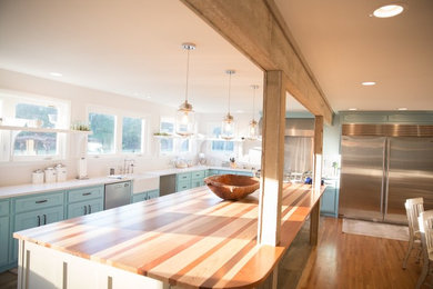 Example of a large transitional l-shaped medium tone wood floor and brown floor eat-in kitchen design in Nashville with a farmhouse sink, shaker cabinets, blue cabinets, white backsplash, stainless steel appliances and an island
