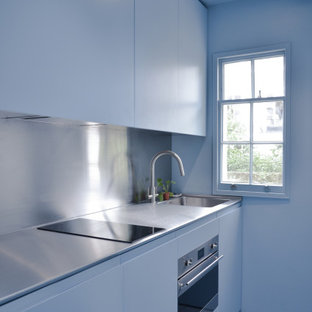 Inspiration for a small contemporary galley kitchen in London with an integrated sink, flat-panel cabinets, blue cabinets, stainless steel benchtops, stainless steel appliances, ceramic floors and blue floor.