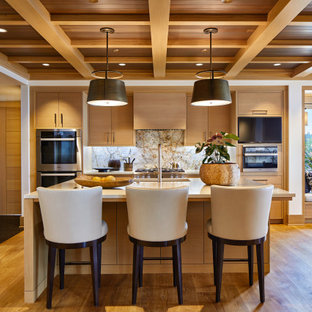 Large transitional open concept kitchen appliance - Open concept kitchen - large transitional l-shaped medium tone wood floor, brown floor, exposed beam and wood ceiling open concept kitchen idea in Seattle with an undermount sink, flat-panel cabinets, medium tone wood cabinets, gray backsplash, stainless steel appliances, an island, beige countertops, solid surface countertops and granite backsplash