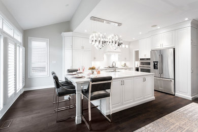 Mid-sized transitional l-shaped dark wood floor and brown floor kitchen photo in Toronto with an undermount sink, raised-panel cabinets, white cabinets, stainless steel appliances, an island, white countertops, white backsplash, marble backsplash and quartzite countertops