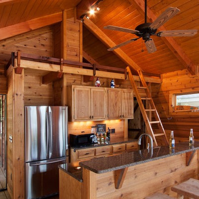 Mid-sized mountain style galley medium tone wood floor open concept kitchen photo in Other with recessed-panel cabinets, stainless steel appliances, light wood cabinets, granite countertops, wood backsplash and an island