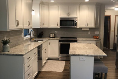 Inspiration for a mid-sized timeless u-shaped vinyl floor and gray floor eat-in kitchen remodel in Other with a double-bowl sink, flat-panel cabinets, white cabinets, granite countertops, gray backsplash, ceramic backsplash, stainless steel appliances, an island and gray countertops