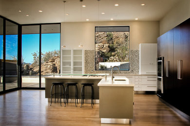 Example of a mid-sized trendy l-shaped light wood floor kitchen design in Phoenix with an undermount sink, flat-panel cabinets, dark wood cabinets, quartz countertops, white backsplash, stainless steel appliances and an island
