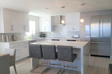 Small modern l-shaped open plan kitchen in Miami with a submerged sink, flat-panel cabinets, white cabinets, engineered stone countertops, multi-coloured splashback, ceramic splashback, stainless steel appliances, marble flooring, an island and grey floors.