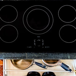 Design ideas for a mid-sized transitional u-shaped open plan kitchen in Miami with recessed-panel cabinets, medium wood cabinets, soapstone benchtops, black appliances, porcelain floors, pink floor and black benchtop.