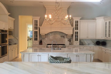 Large classic u-shaped enclosed kitchen in Miami with a submerged sink, shaker cabinets, white cabinets, marble worktops, grey splashback, marble splashback, stainless steel appliances, travertine flooring, an island and beige floors.