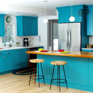 Mid-sized eclectic eat-in kitchen pictures - Eat-in kitchen - mid-sized eclectic l-shaped light wood floor and brown floor eat-in kitchen idea in Milwaukee with an integrated sink, turquoise cabinets, wood countertops, white backsplash, stainless steel appliances, an island, flat-panel cabinets and white countertops