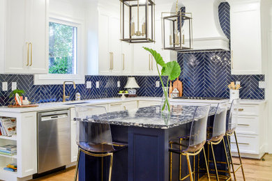 Example of a mid-sized transitional l-shaped medium tone wood floor and brown floor enclosed kitchen design in Other with an undermount sink, flat-panel cabinets, white cabinets, quartz countertops, blue backsplash, porcelain backsplash, stainless steel appliances, an island and white countertops