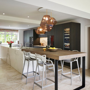 This is an example of a contemporary galley kitchen in Cheshire with flat-panel cabinets, dark wood cabinets, black appliances, an island, beige floors and white worktops.