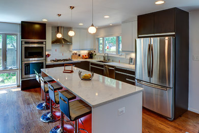 Eat-in kitchen - mid-sized contemporary l-shaped medium tone wood floor and brown floor eat-in kitchen idea in DC Metro with flat-panel cabinets, white cabinets, quartz countertops, white backsplash, ceramic backsplash, stainless steel appliances, an island, an undermount sink and white countertops