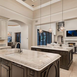 This is an example of an expansive mediterranean u-shaped separate kitchen in Phoenix with an undermount sink, recessed-panel cabinets, quartzite benchtops, multi-coloured splashback, porcelain splashback, stainless steel appliances, porcelain floors, multiple islands, multi-coloured floor, beige benchtop and dark wood cabinets.