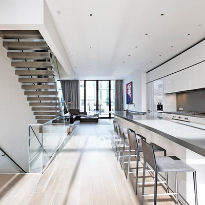 Kitchen - modern galley kitchen idea in New York with flat-panel cabinets, white cabinets, gray backsplash and stainless steel appliances