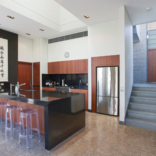 This is an example of a large asian galley kitchen in Sydney with an undermount sink, flat-panel cabinets, medium wood cabinets, quartz benchtops, black splashback, stone slab splashback, stainless steel appliances, concrete floors, grey floor, black benchtop and a peninsula.