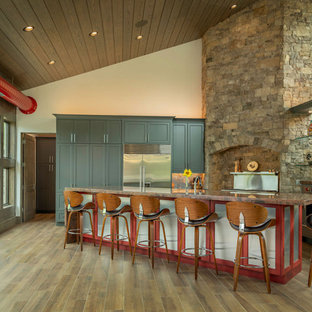 This is an example of a contemporary u-shaped open plan kitchen in Other with a double-bowl sink, flat-panel cabinets, grey cabinets, granite benchtops, grey splashback, glass tile splashback, stainless steel appliances, porcelain floors, with island, brown floor and red benchtop.