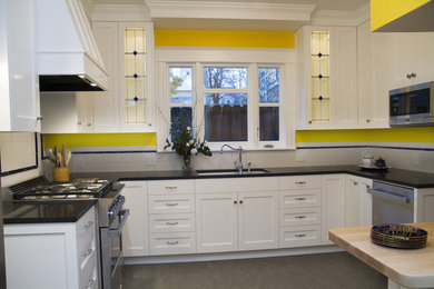 Example of a mid-sized trendy u-shaped enclosed kitchen design in Portland with an undermount sink, recessed-panel cabinets, white cabinets, granite countertops, white backsplash, ceramic backsplash and stainless steel appliances