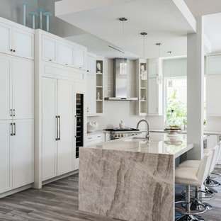 Ispirazione per una cucina a L tradizionale con isola, lavello sottopiano, ante in stile shaker, ante bianche, elettrodomestici in acciaio inossidabile, pavimento grigio e top beige