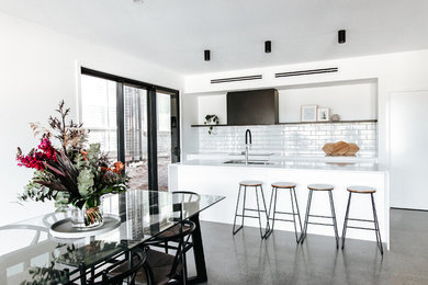 Kitchen - mid-sized modern galley concrete floor and gray floor kitchen idea in Wollongong with a double-bowl sink, flat-panel cabinets, white cabinets, quartz countertops, white backsplash, ceramic backsplash, stainless steel appliances, an island and white countertops