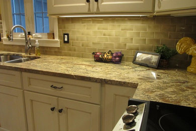 Example of a mid-sized l-shaped eat-in kitchen design in New York with an undermount sink, recessed-panel cabinets, beige cabinets, granite countertops, green backsplash, subway tile backsplash, stainless steel appliances, no island and multicolored countertops