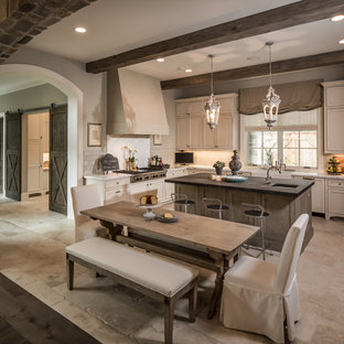 Ispirazione per una cucina chic di medie dimensioni con lavello stile country, ante con riquadro incassato, elettrodomestici in acciaio inossidabile, paraspruzzi bianco, paraspruzzi in pietra calcarea, ante bianche, top in quarzite, pavimento in pietra calcarea e pavimento beige