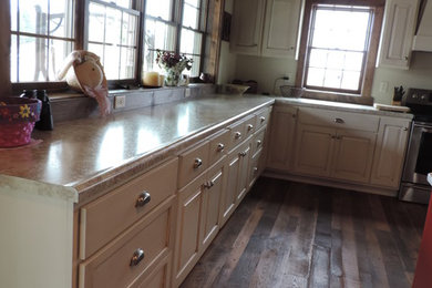 Large mountain style l-shaped medium tone wood floor open concept kitchen photo in Other with a farmhouse sink, raised-panel cabinets, white cabinets, marble countertops, stainless steel appliances and an island