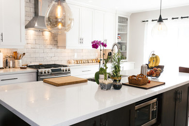 Example of a large transitional single-wall dark wood floor enclosed kitchen design in Toronto with a farmhouse sink, shaker cabinets, white cabinets, granite countertops, white backsplash, stone tile backsplash, stainless steel appliances and an island