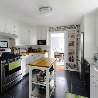 Inspiration for a traditional separate kitchen in Boston with an integrated sink, flat-panel cabinets, white cabinets, stainless steel benchtops, white splashback, subway tile splashback and stainless steel appliances.