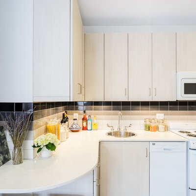 Small trendy l-shaped porcelain tile eat-in kitchen photo in Boston with a drop-in sink, flat-panel cabinets, white cabinets, quartz countertops, white backsplash, ceramic backsplash, white appliances and no island