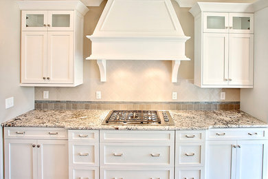 Diseño de cocina clásica renovada con armarios tipo vitrina, puertas de armario blancas, encimera de granito, salpicadero multicolor, electrodomésticos de acero inoxidable y una isla