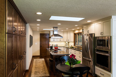 Example of a transitional u-shaped dark wood floor eat-in kitchen design in Seattle with a drop-in sink, recessed-panel cabinets, white cabinets, granite countertops, brown backsplash, ceramic backsplash, stainless steel appliances and an island
