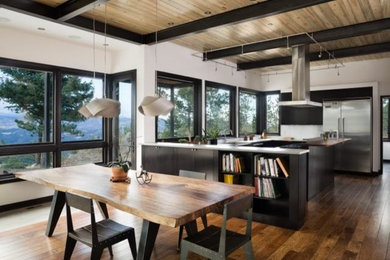 Example of a huge trendy u-shaped medium tone wood floor and brown floor eat-in kitchen design in Denver with a farmhouse sink, flat-panel cabinets, black cabinets, quartzite countertops, white backsplash, subway tile backsplash, stainless steel appliances and an island