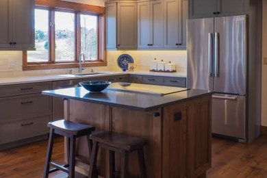 Example of a mid-sized eclectic medium tone wood floor and brown floor kitchen design in Other with shaker cabinets, medium tone wood cabinets, white backsplash, subway tile backsplash, stainless steel appliances and an island