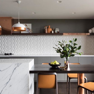 Photo of a contemporary galley kitchen in Sydney with flat-panel cabinets, grey cabinets, white splashback, stainless steel appliances, with island, brown floor and white benchtop.