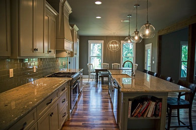 Eat-in kitchen - mid-sized contemporary galley medium tone wood floor and beige floor eat-in kitchen idea in Other with a farmhouse sink, recessed-panel cabinets, beige cabinets, granite countertops, gray backsplash, glass tile backsplash, stainless steel appliances and an island