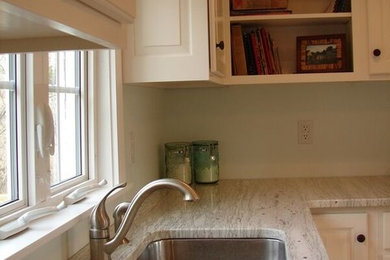 Example of a mid-sized transitional l-shaped medium tone wood floor eat-in kitchen design in Portland Maine with a double-bowl sink, white cabinets, granite countertops and white appliances
