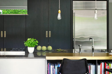 Große Moderne Wohnküche mit flächenbündigen Schrankfronten, schwarzen Schränken, Küchengeräten aus Edelstahl und Kücheninsel in London
