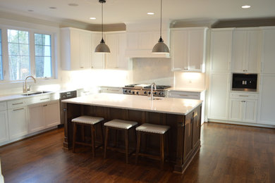 Large arts and crafts l-shaped dark wood floor kitchen photo in Raleigh with shaker cabinets, white cabinets, white backsplash, stainless steel appliances and an island