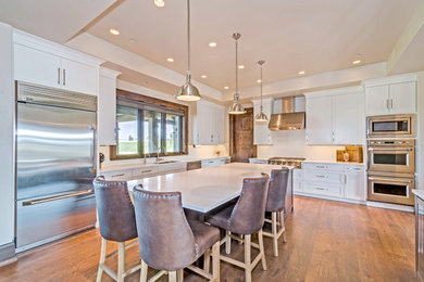 Eat-in kitchen - large traditional l-shaped light wood floor eat-in kitchen idea in Other with a drop-in sink, flat-panel cabinets, distressed cabinets, granite countertops, white backsplash, stainless steel appliances, an island and subway tile backsplash