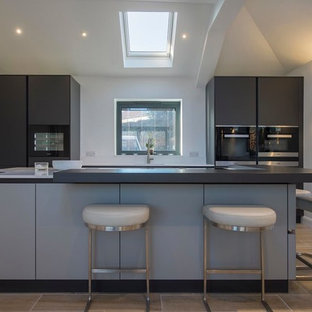 Contemporary kitchen in Other with flat-panel cabinets, black appliances, an island, beige floors and grey cabinets.