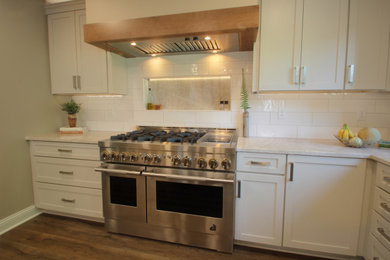Mid-sized transitional l-shaped brown floor eat-in kitchen photo in Other with an undermount sink, shaker cabinets, white cabinets, quartzite countertops, white backsplash, ceramic backsplash, stainless steel appliances, an island and beige countertops