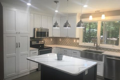 Example of a large arts and crafts u-shaped ceramic tile eat-in kitchen design in Other with a farmhouse sink, shaker cabinets, white cabinets, quartz countertops, gray backsplash, ceramic backsplash, stainless steel appliances and an island