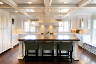 Inspiration for a large timeless u-shaped dark wood floor kitchen remodel in Kansas City with a farmhouse sink, raised-panel cabinets, white cabinets, subway tile backsplash, paneled appliances and an island