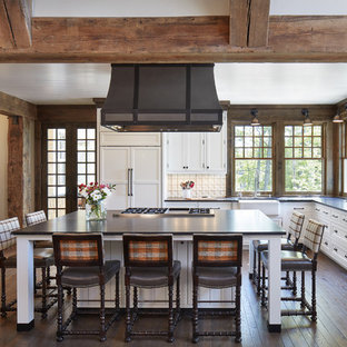 Large coastal open concept kitchen ideas - Example of a large beach style l-shaped medium tone wood floor and brown floor open concept kitchen design in Minneapolis with white cabinets, white backsplash, porcelain backsplash, paneled appliances, an island, a farmhouse sink, shaker cabinets and solid surface countertops