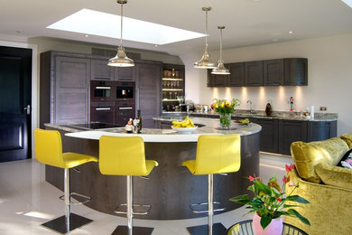 Large contemporary l-shaped open plan kitchen in Sussex with a submerged sink, dark wood cabinets, ceramic flooring, an island and beige floors.