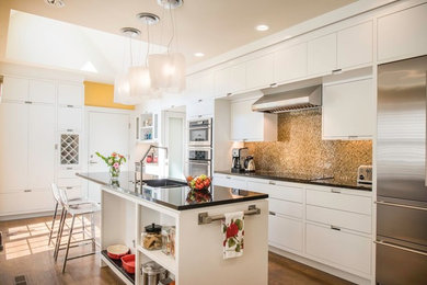 Inspiration for a mid-sized contemporary l-shaped medium tone wood floor eat-in kitchen remodel in Cleveland with a double-bowl sink, flat-panel cabinets, white cabinets, mosaic tile backsplash, stainless steel appliances, an island, solid surface countertops and beige backsplash
