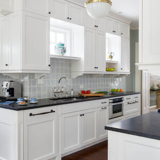 Ejemplo de cocina tradicional renovada con fregadero bajoencimera, armarios estilo shaker, puertas de armario blancas, salpicadero azul, salpicadero de azulejos de vidrio, electrodomésticos de acero inoxidable y suelo de madera oscura