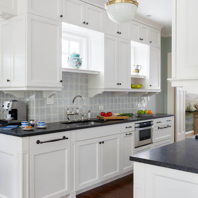 Example of a transitional dark wood floor kitchen design in Boston with an undermount sink, shaker cabinets, white cabinets, blue backsplash, glass tile backsplash and stainless steel appliances