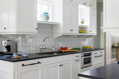 Immagine di una cucina chic con lavello sottopiano, ante in stile shaker, ante bianche, paraspruzzi blu, paraspruzzi con piastrelle di vetro, elettrodomestici in acciaio inossidabile e parquet scuro